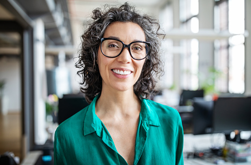 Image of a smiling woman with curly hair and wearing glasses, at Martin Periodontics in Mason, OH.