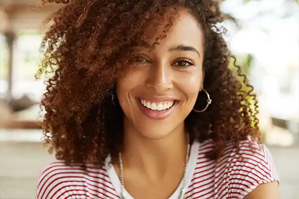 Black woman with curly hair smiling after appointment at Martin Periodontics in Mason, OH