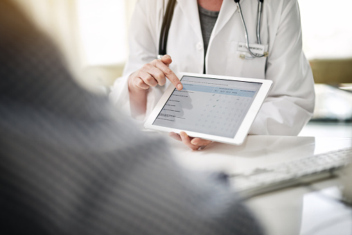 Dentist reviewing digital patient forms on a tablet with a patient