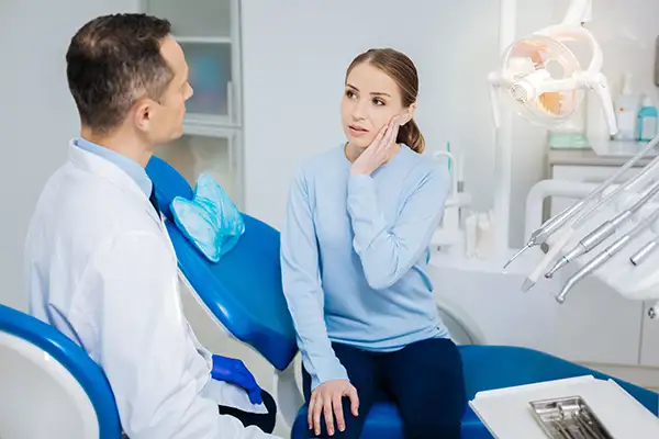 Woman speaking with dentist holding her jaw