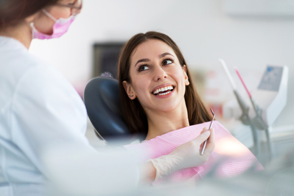 Woman smiling in a dental chair learning about the dental services at Martin Periodontics in Mason & North Cincinnati, OH